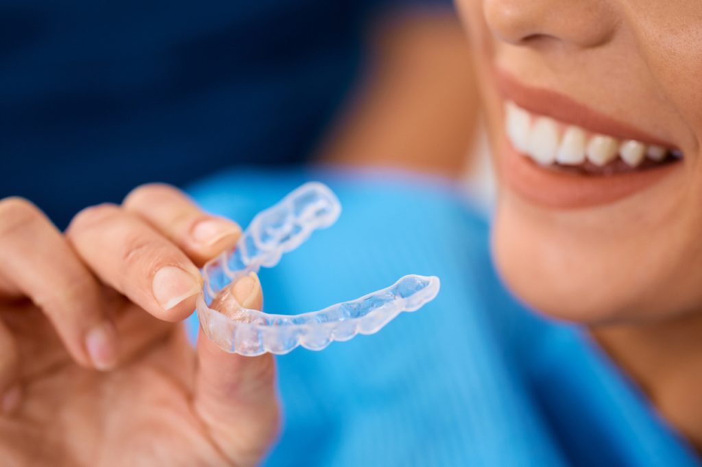 Close up of woman using orthodontic teeth aligner.